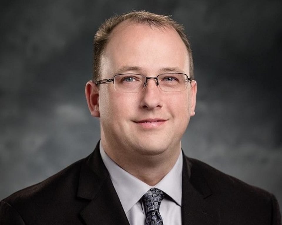 a man wearing a suit and tie smiling at the camera