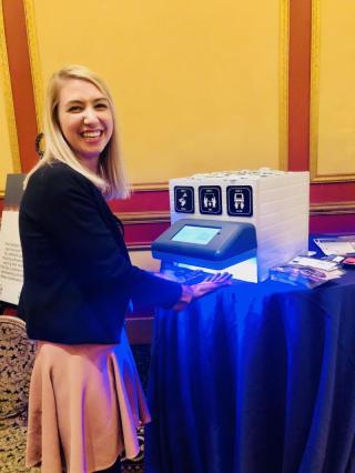 a woman sitting at a desk with a laptop and smiling at the camera