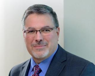 a man wearing a suit and tie smiling and looking at the camera