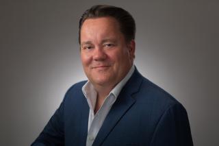 a man wearing a suit and tie smiling and looking at the camera