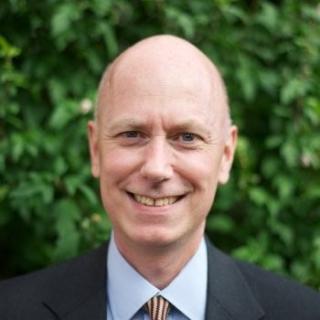 a man wearing a suit and tie smiling at the camera