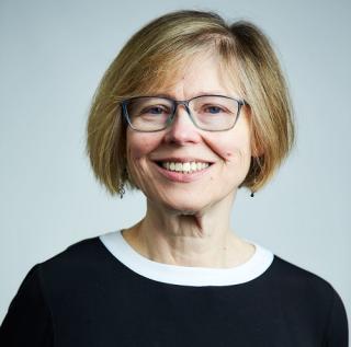 a woman wearing glasses and smiling at the camera