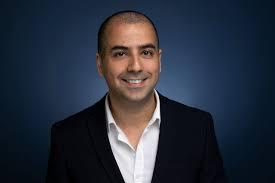 a man wearing a suit and tie smiling at the camera