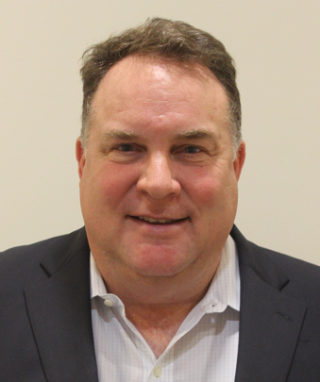 a man wearing a suit and tie smiling at the camera