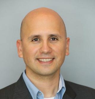 a man wearing a suit and tie smiling at the camera