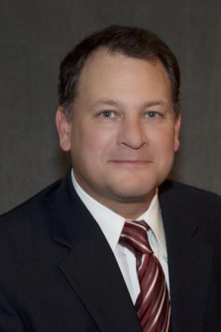 a man wearing a suit and tie smiling at the camera