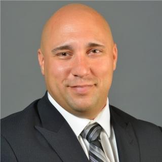 a man wearing a suit and tie smiling at the camera