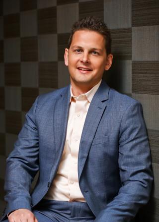 a man wearing a suit and tie smiling at the camera