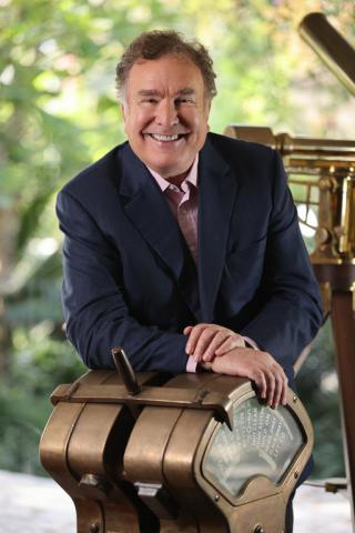 Richard D. Fain wearing a suit and tie sitting on a bench