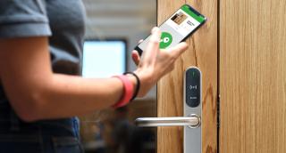 a hand holding a remote control on a wooden surface