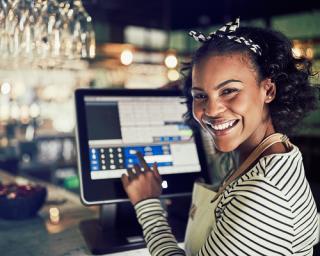 a woman sitting at a table with a laptop and smiling at the camera