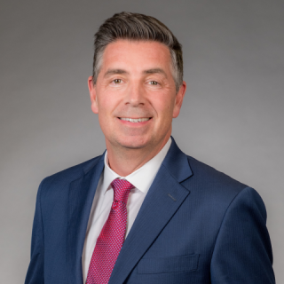 Chip Rogers wearing a suit and tie smiling at the camera