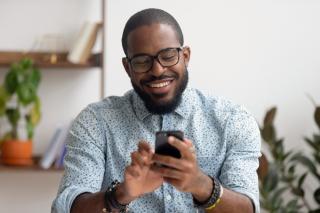 man smiling while looking at his cell phone