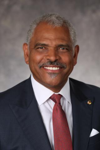 Arnold W. Donald wearing a suit and tie smiling at the camera