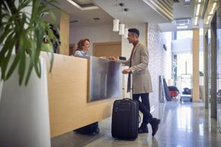 a person holding luggage at hotel desk
