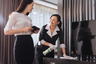 Housekeeping staff using a tablet while cleaning a guestroom