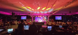 a group of people sitting on stage with stage lights and an audience