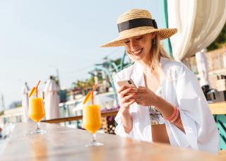 Smiling woman using phone at outdoor bar