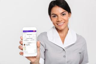 housekeeper holding up a mobile phone with housekeeping app