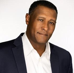 a man wearing a suit and tie smiling and looking at the camera