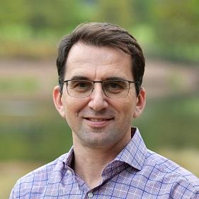 a man wearing glasses and smiling at the camera