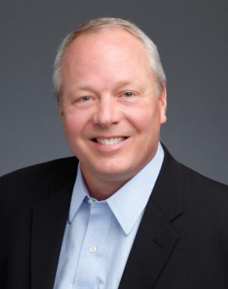 a man wearing a suit and tie smiling at the camera