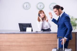 an unhappy hotel guest in front of the check-in desk