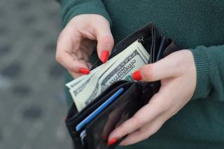 a person looking through the money in their wallet