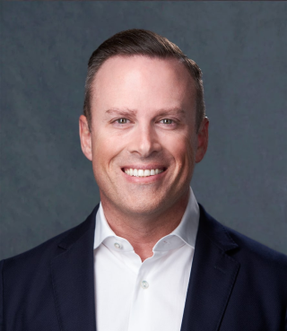 a man wearing a suit and tie smiling at the camera