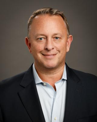 a man wearing a suit and tie smiling and looking at the camera