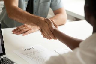 two people shaking hands, piece of paper that reads resume