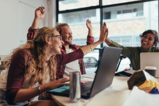people in an office high-fiving and cheering
