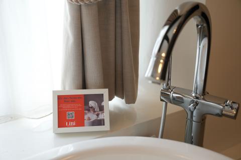 Tub filled with water w/ QR code next to it advertising spa products are for sale