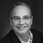 a man wearing glasses and smiling at the camera