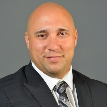 a man wearing a suit and tie smiling at the camera