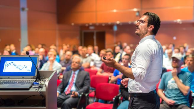 person standing up at event using microphone